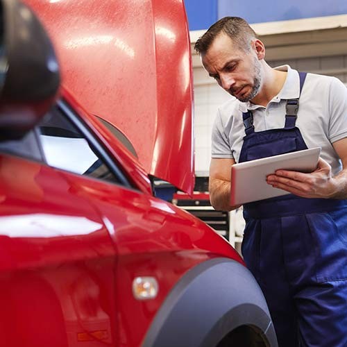 Mechaniker prüft Auto mit Tablet in Werkstatt