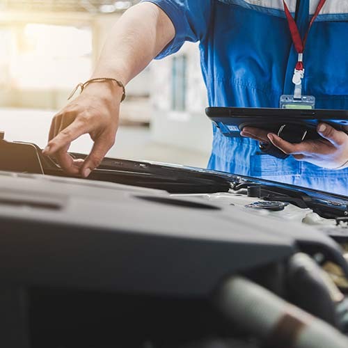 Mechaniker überprüft Auto mit Tablet in Werkstatt